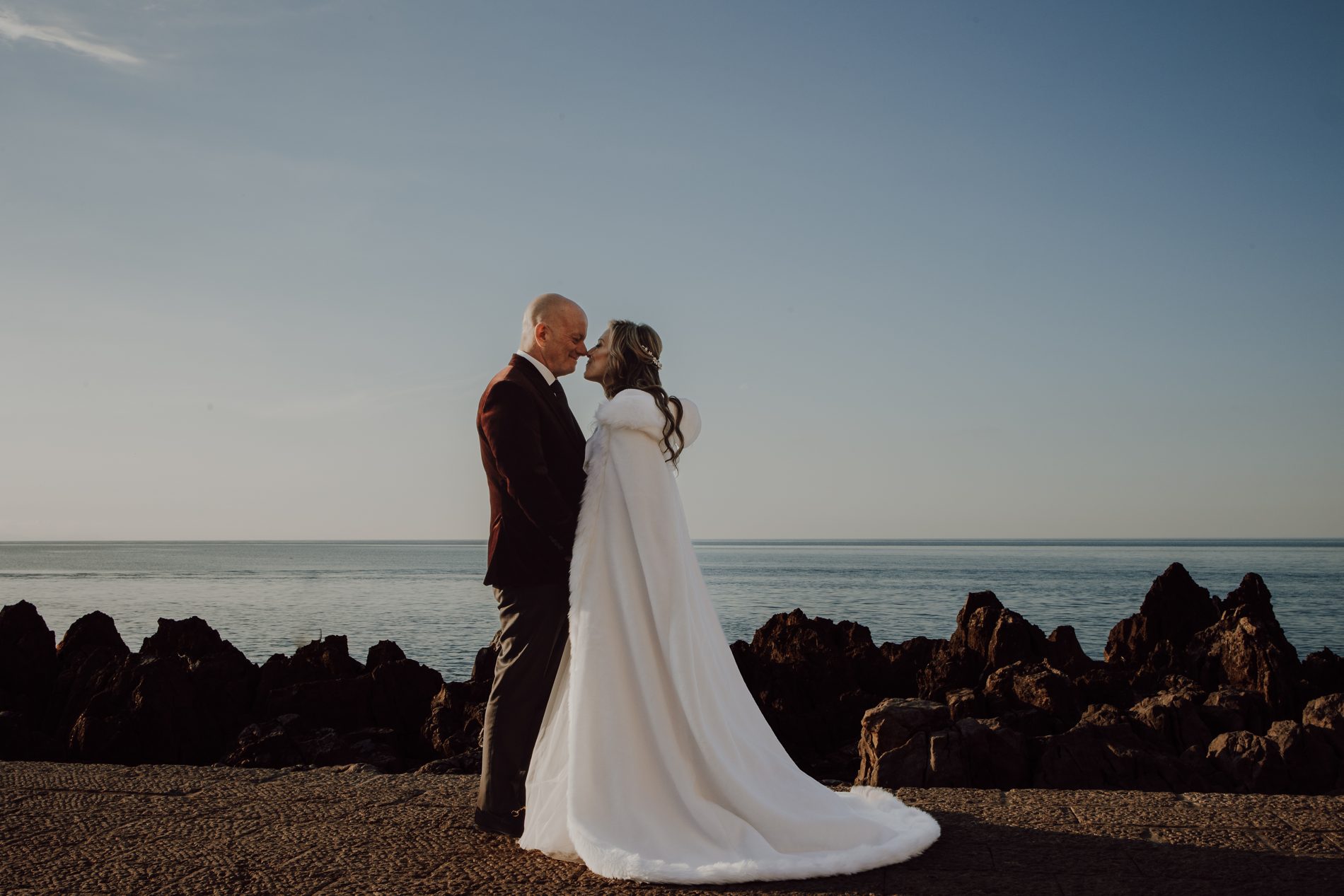 A kiss on the rocks, the bride in a white fur cape