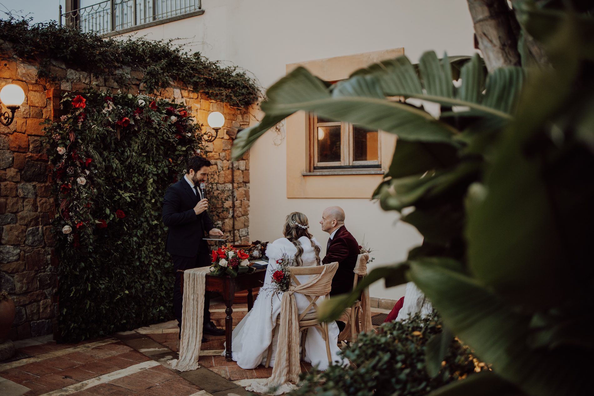 The ceremony, glimpsed through the greenery