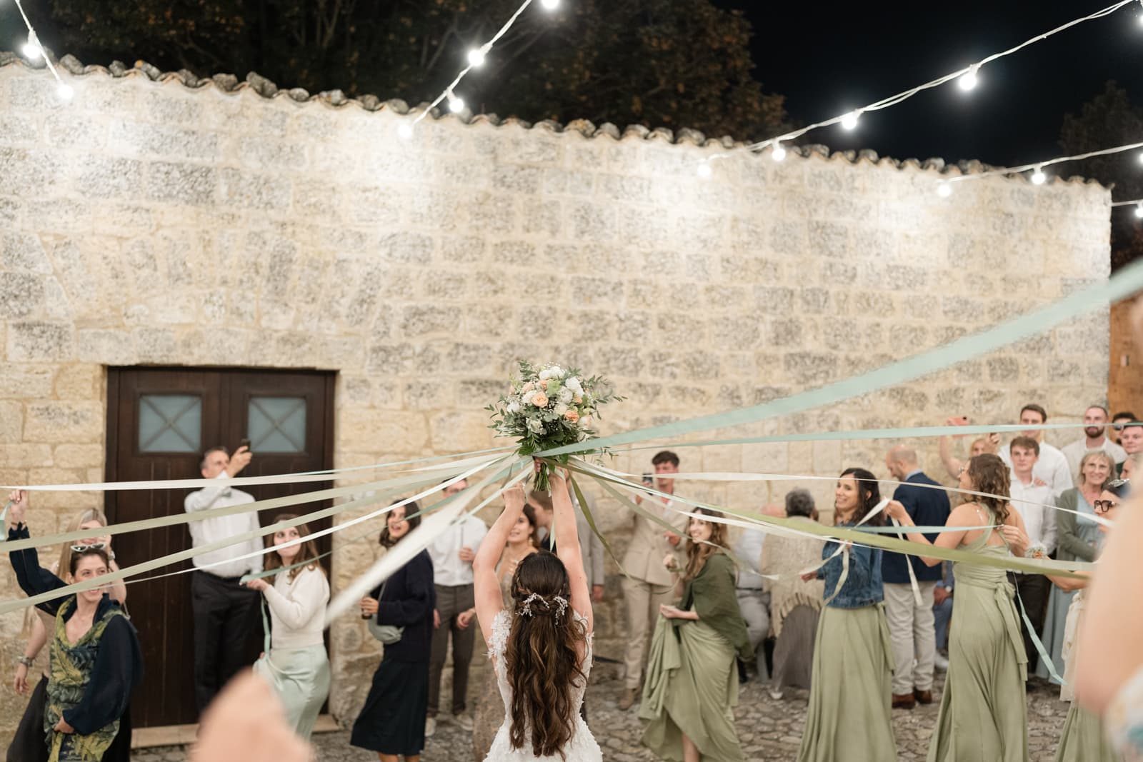 Bouquet toss with ribbons at night