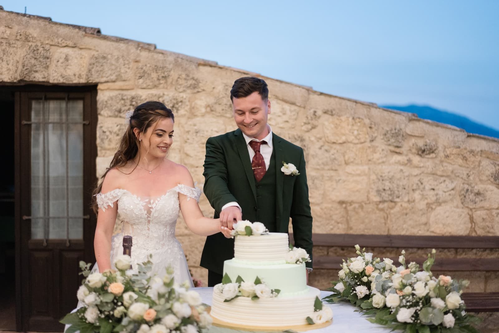 Cutting the cake at dusk against a stone wall
