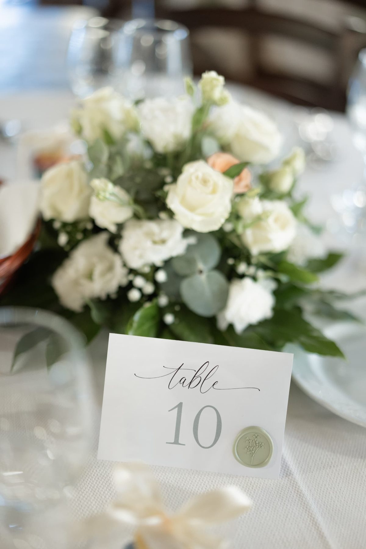 White and peach floral centrepiece with table number
