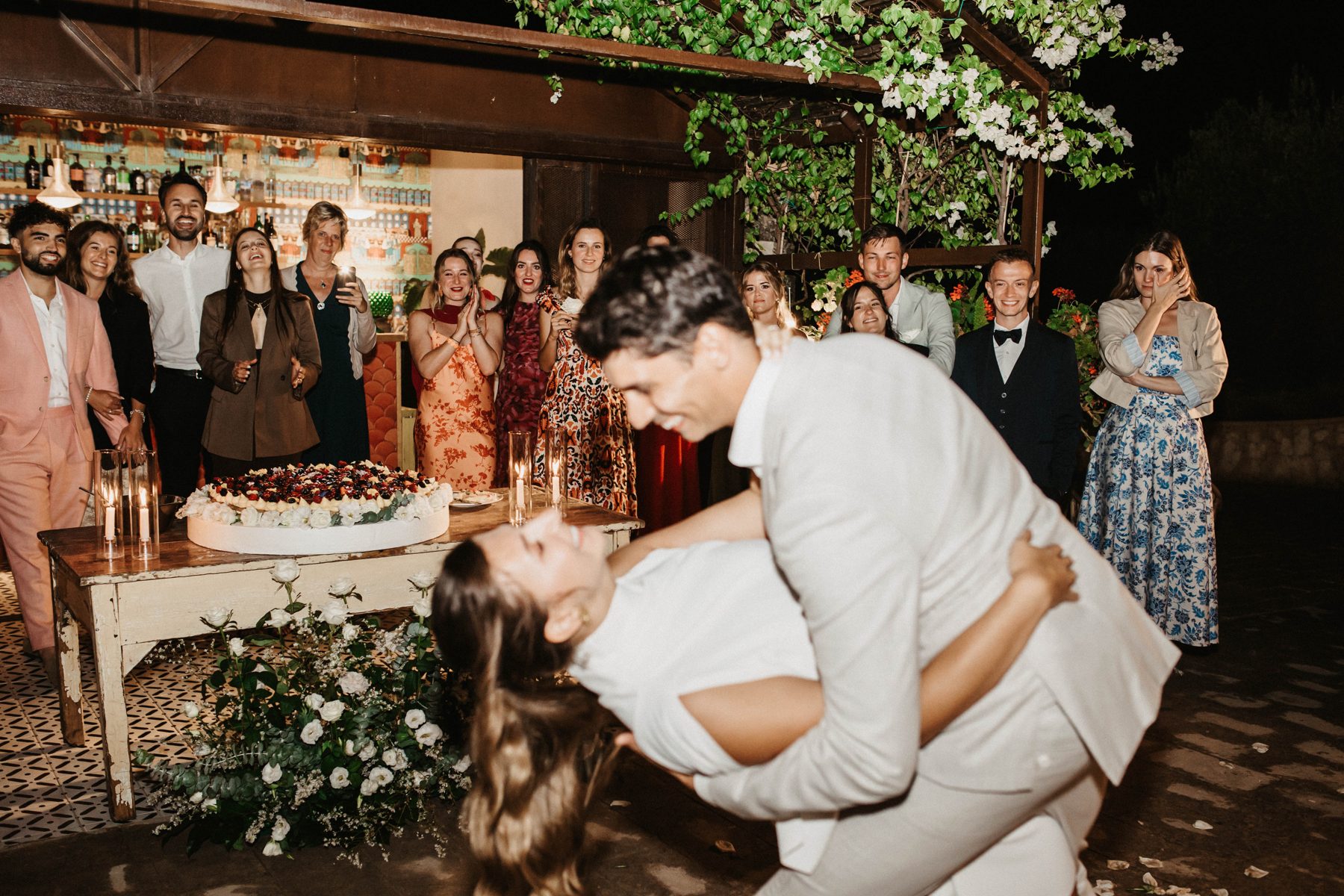 A dip and a kiss beside the cake as guests cheer