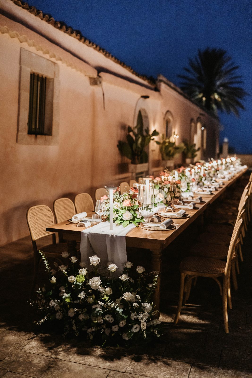 The long dinner table laid outside under the night sky
