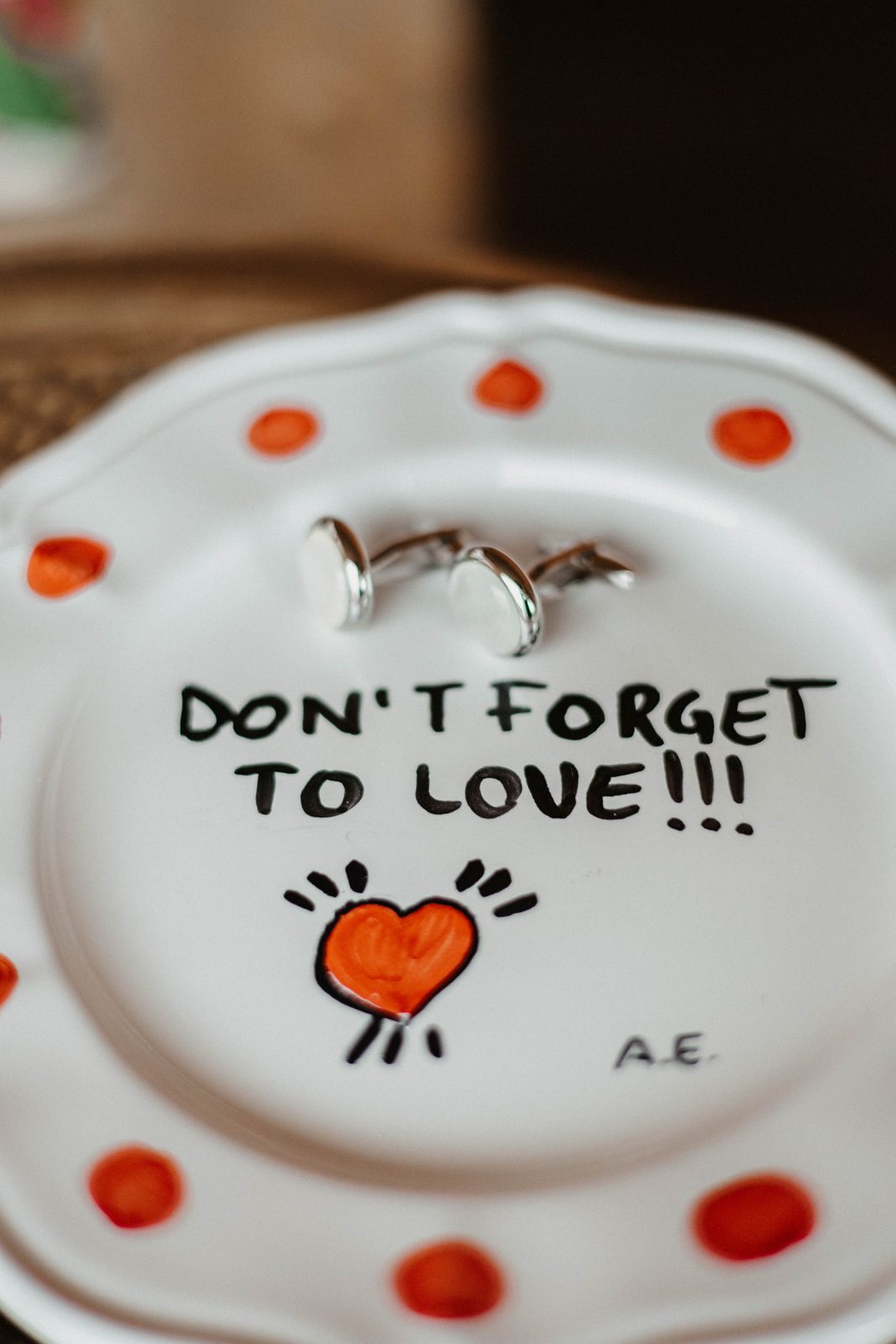 Cufflinks on a hand-painted plate reading Don't forget to love