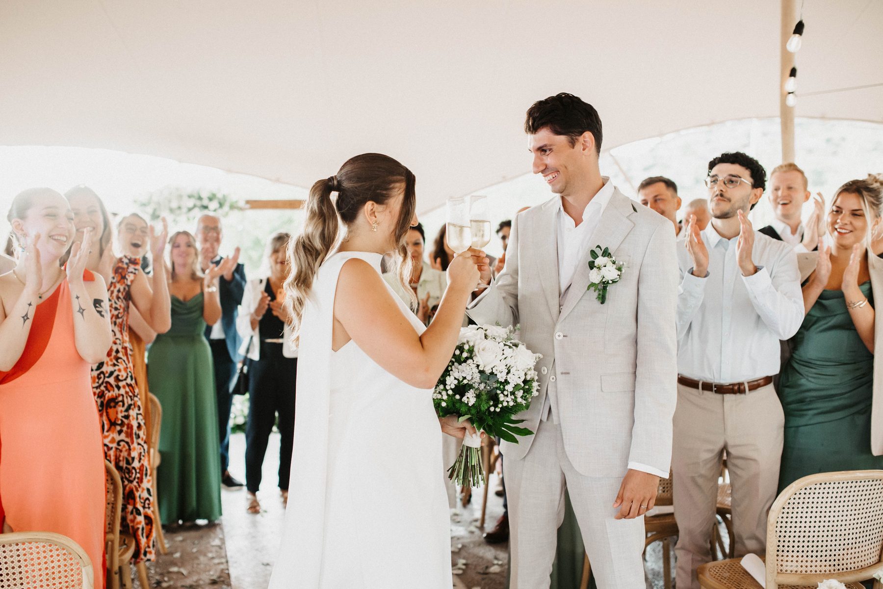 Claire & Julian toast as their guests applaud