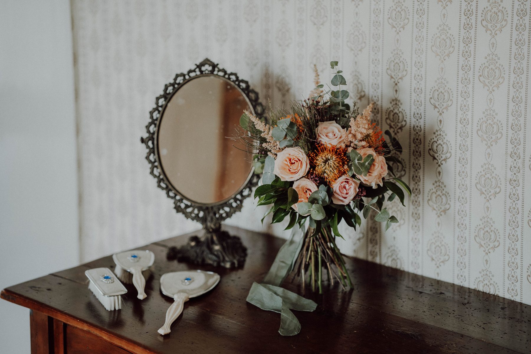 Bridal bouquet beside a vintage mirror during the morning preparations