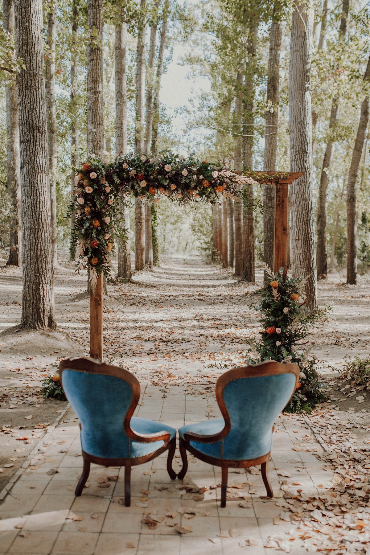 Woodland ceremony arch with vintage velvet chairs