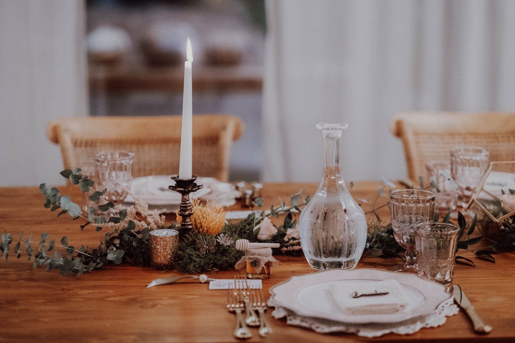 Table detail with candlelight and a brass butterfly