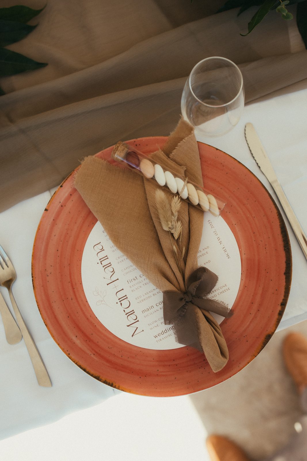 A place setting in cream, brown and terracotta with the menu for Marcin & Karina