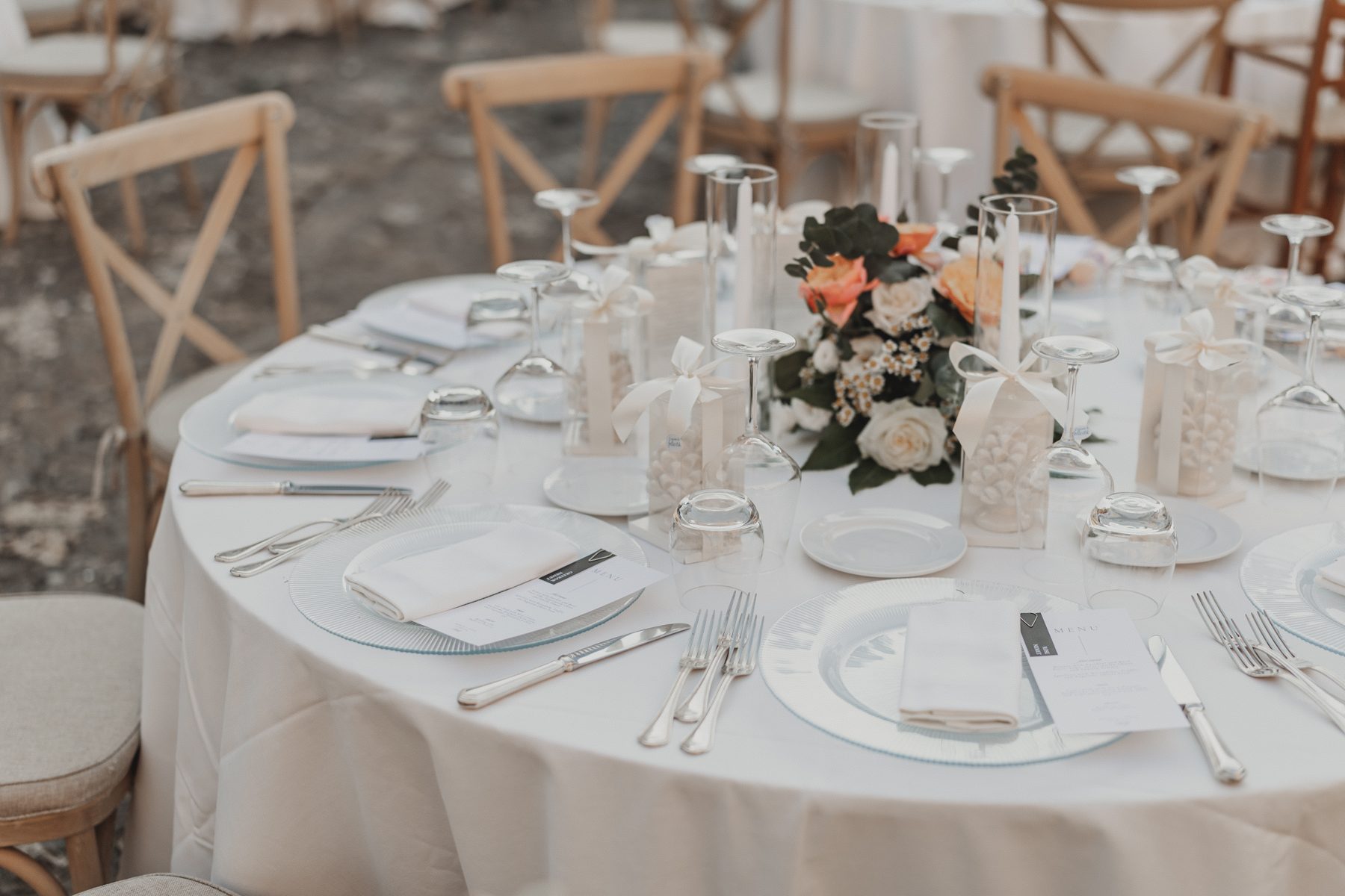 A minimal white table with black-and-white menus and a small Sicilian pinecone at each place