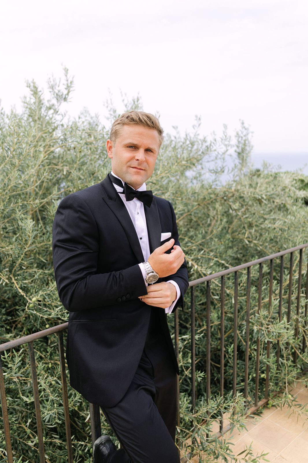 The groom on the stone terrace, olive trees and the sea behind