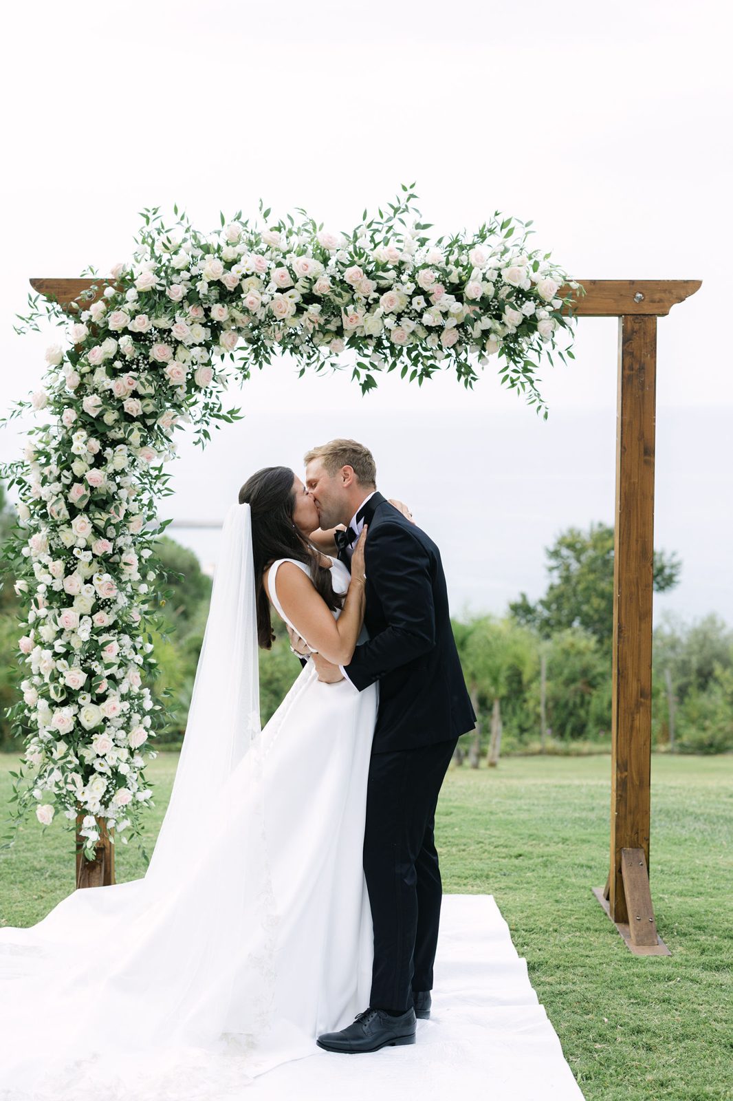 First kiss beneath the floral arch over the Kalura coast