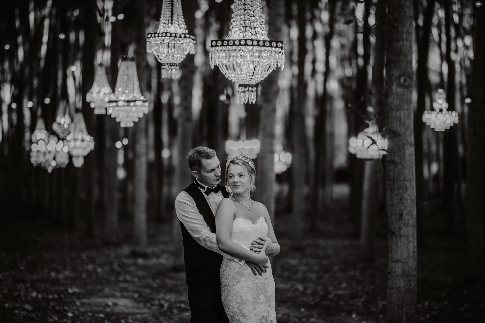 The couple beneath a canopy of crystal chandeliers, in black and white