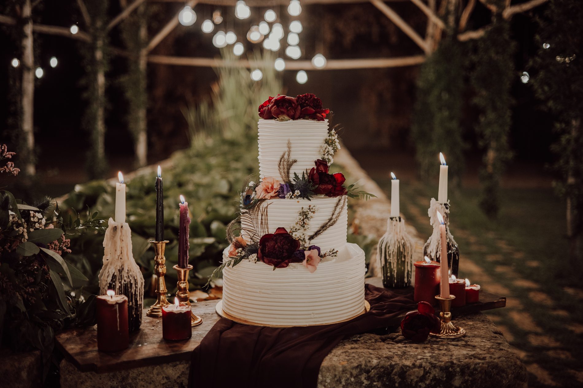 The cake, framed by dark candles — black, purple and pink