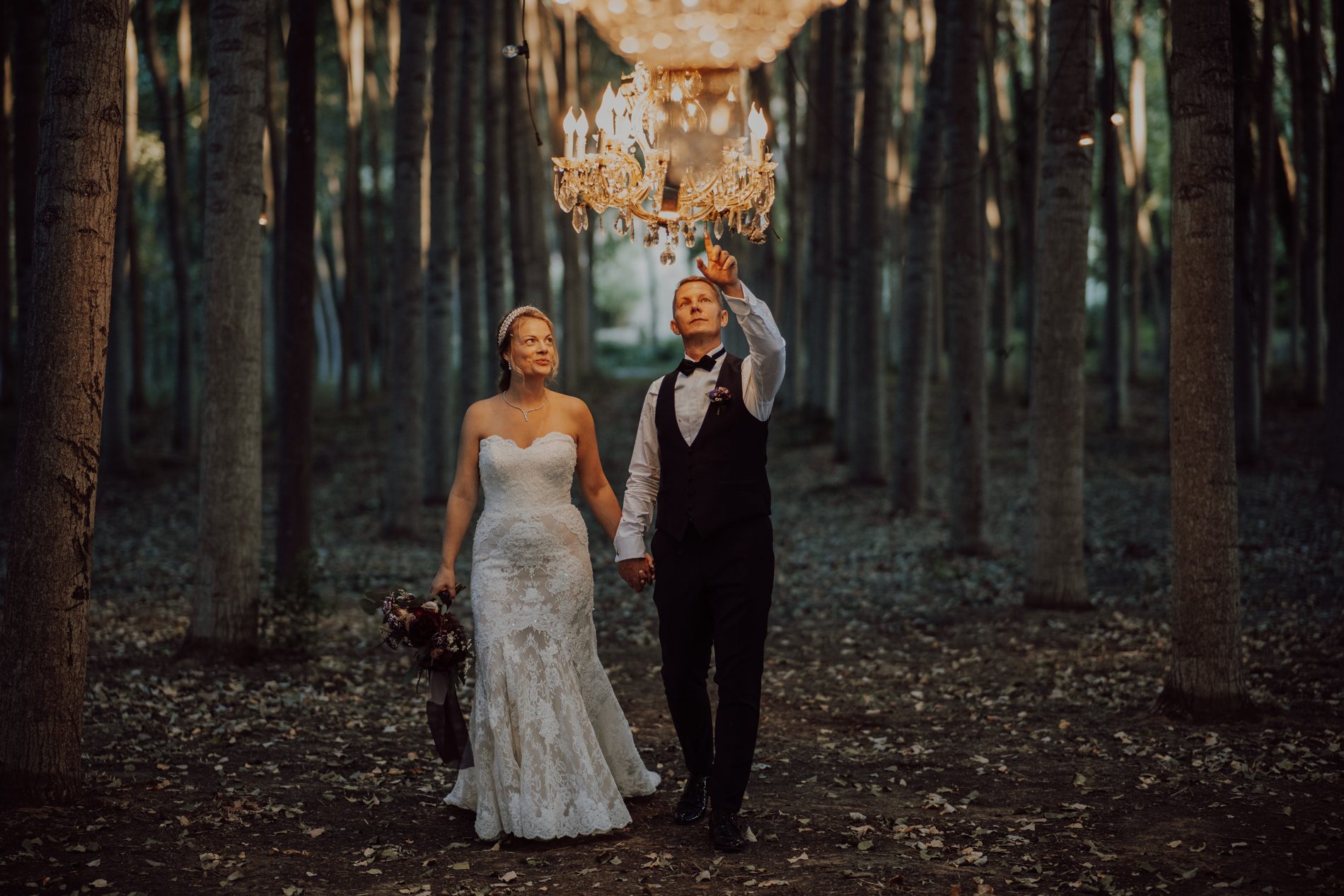 A forest hung with chandeliers — the groom points one out